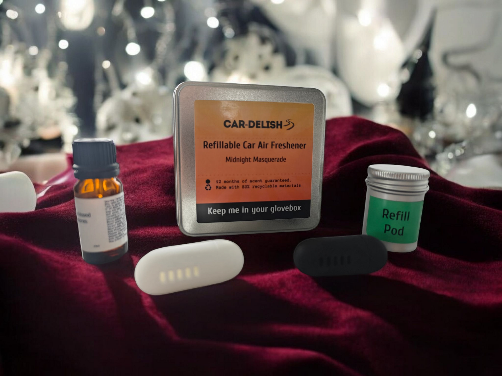 A picture showing the Car Delish Packaging Tin, colour options of the air freshener, the bottle of top of scent and the refill tin for the Midnight Masquerade scent option